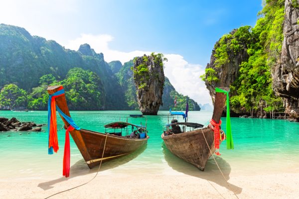 James Bond island con le classiche imbarcazioni tailandesi di legno arenate sulla spiaggia a Phang Nga bay, Thailandia