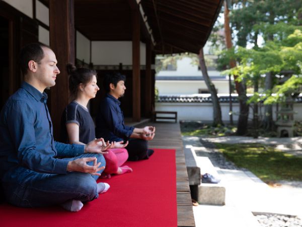 3 persone che meditano nel giardino del tempio