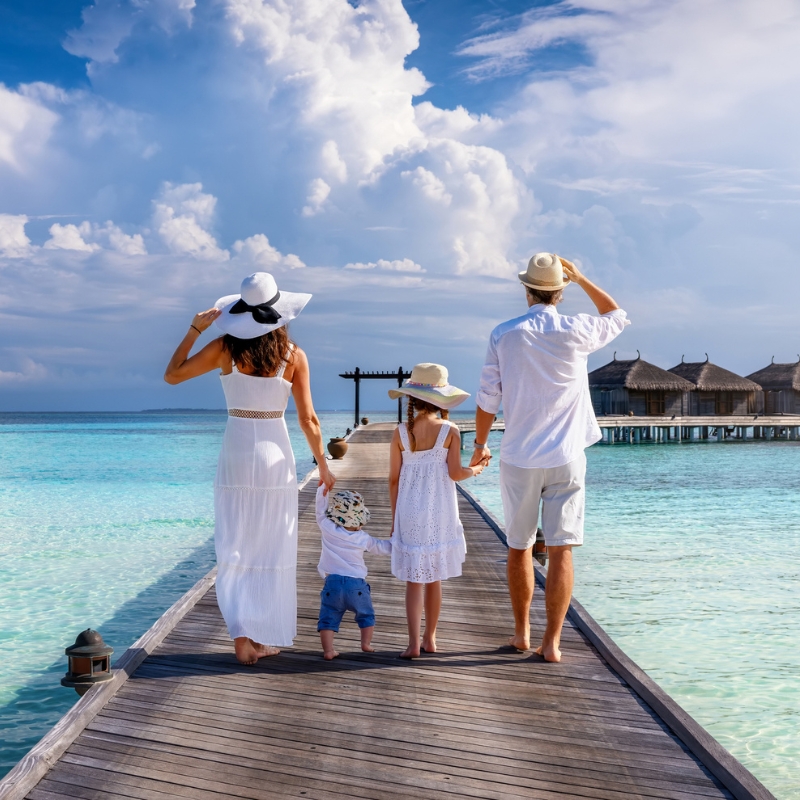 Famiglia con bambini che cammina nella bassa laguna turchese di un resort family-friendly Famiglia con bambini che cammina nella bassa laguna turchese di un resort family-friendly